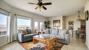 A spacious living room with a gray sofa, a wooden coffee table, and a ceiling fan. - Golf Course Views & Private Deck: Mesquite Condo! (Mesquite)