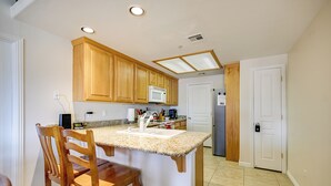 A kitchen with wooden cabinets, a granite countertop, a microwave, and a sink. - Golf Course Views & Private Deck: Mesquite Condo! (Mesquite)