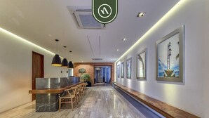 A modern hotel lobby with a marble floor, wooden reception desk, pendant lighting, and framed artwork on the walls. - The Park 506 | 2BR/2BA | Puerto Vallarta | Pool, Gym (Puerto Vallarta)