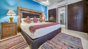 A bedroom with a large bed, two bedside tables, a wardrobe, and a bathroom visible through an open door. - The Park 506 | 2BR/2BA | Puerto Vallarta | Pool, Gym (Puerto Vallarta)