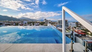 A rooftop infinity pool with a clear view of the cityscape and mountains in the background. - Amazing 1BR - Rooftop Pool in Versalles (Puerto Vallarta)