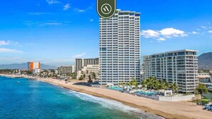 A coastal hotel with multiple high-rise buildings, a beach, and clear blue waters.
