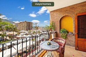 Uma varanda com mesa e cadeiras, um muro de tijolos e uma porta amarela.