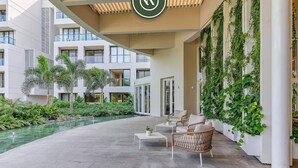 A modern outdoor area with a concrete floor, a seating area with wicker chairs and a table, and a vertical garden wall.