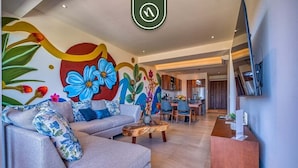 Una sala moderna con sofá, mesa de centro y un mural con diseños florales.