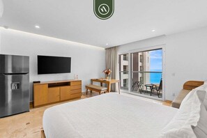 Ein modernes Hotelzimmer mit Bett, Fernseher, Minibar, Schreibtisch und einem Balkon mit Blick.