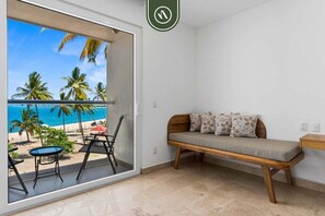 Ein Balkon mit Blick auf den Strand, eine Holzbank und ein Tisch mit Stühlen.