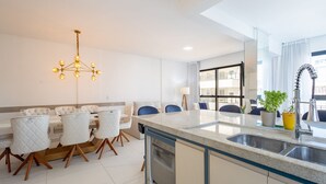 Una cocina moderna con lavavajillas integrado, un comedor con candelabro y vistas a la ciudad a través de amplios ventanales.