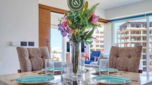 A dining table set with teal plates, clear glasses, and a centerpiece of flowers and greenery. - Zoho Skies T3 703 | 1BR/2BA | PV | Pool, Gym, Views (Puerto Vallarta)