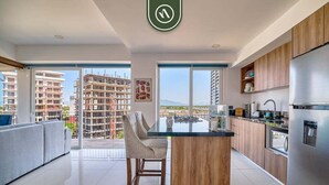 A modern kitchen with a central island, wooden cabinets, and a stainless steel refrigerator. - Zoho Skies T3 703 | 1BR/2BA | PV | Pool, Gym, Views (Puerto Vallarta)