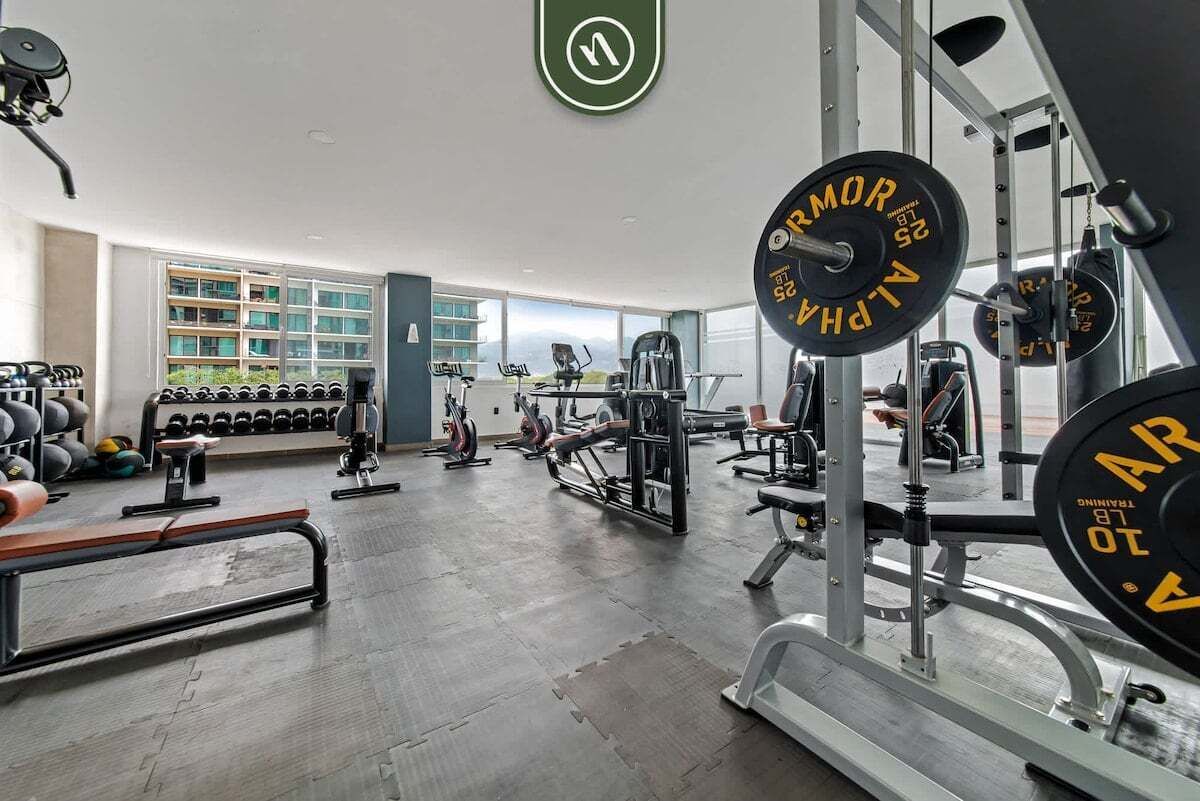 Une salle de sport équipée de matériel de musculation, d’haltères et d’appareils de cardio.