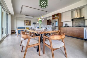 Ein moderner Essbereich mit einem runden Holztisch, sechs Stühlen und einer Blumenvase.