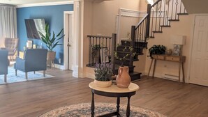 Un salon avec une table ronde, un escalier et un mur bleu.