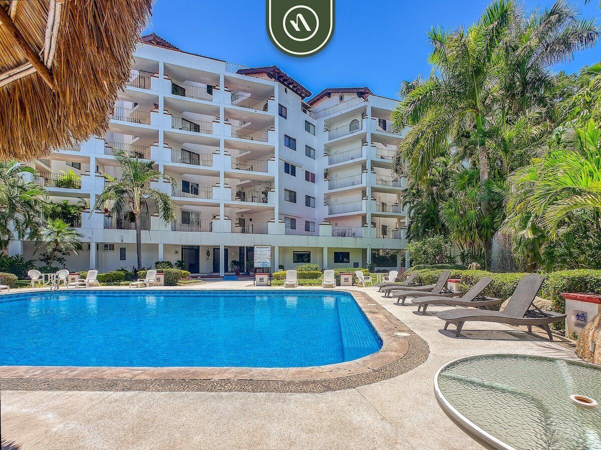 Un hôtel doté d’une piscine, de chaises longues et de palmiers.