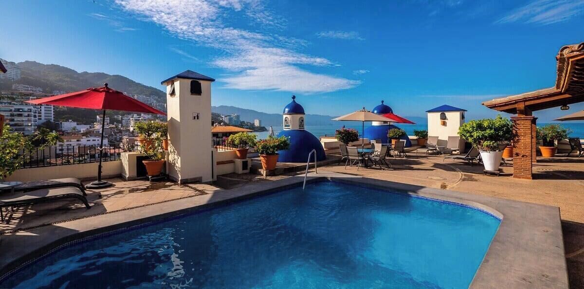 A pool area with lounge chairs, umbrellas, and potted plants.