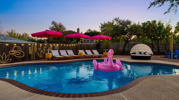 A backyard pool with lounge chairs, a pink flamingo float, and string lights. - NEW Villa w/ Pool•HotTub•GameRoom•Movie•Sleeps20 (Austin)