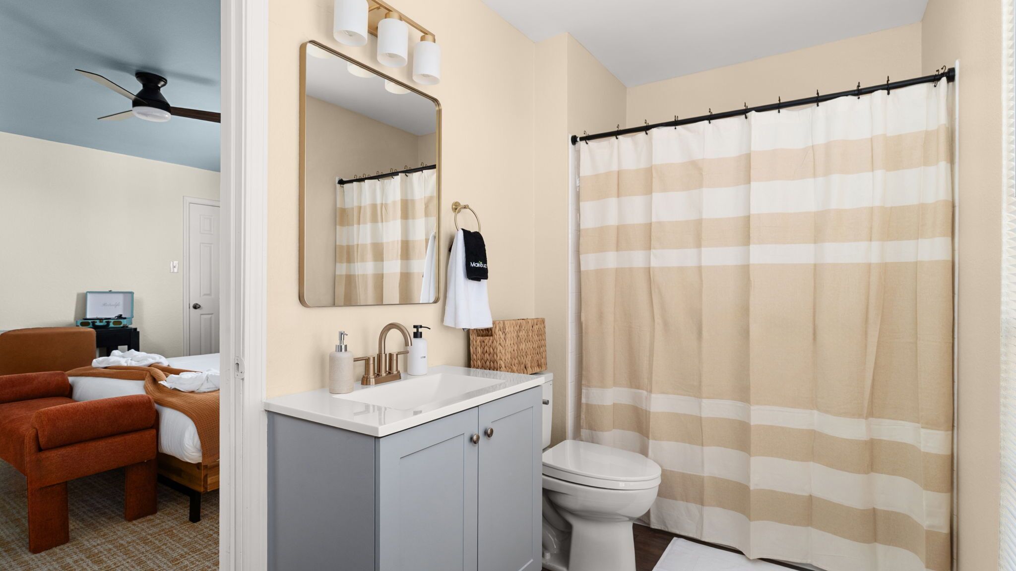 A bathroom with a striped shower curtain, a sink with a mirror, and a toilet.