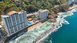 A coastal hotel with multiple balconies, a pool, and a beachside location. - Costa Sur Suite 2 | 1BR/1.5BA Puerto Vallarta, Beachfront Pool & WiFi (Puerto Vallarta)