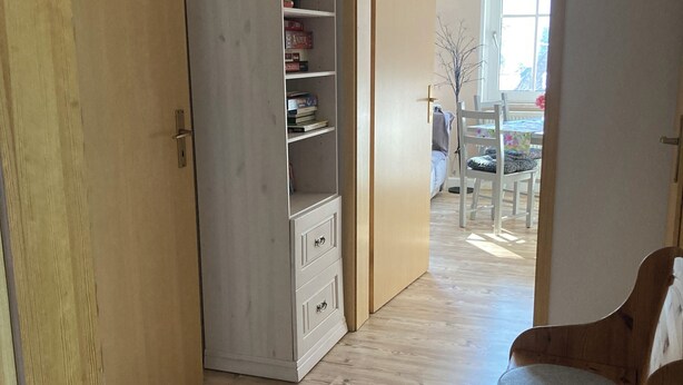 En hall med en garderob i trä, ett vitt skåp och en träbänk.
