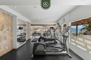 A modern gym with treadmills, elliptical machines, and weight equipment.