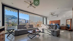 Una sala de estar moderna con un sofá modular, una mesa de centro y vistas de un paisaje urbano a través de grandes ventanales.