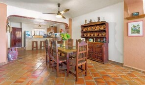 A dining area with a wooden table, chairs, and a ceiling fan.