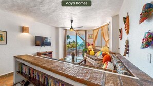 A living room with a sofa, a coffee table, a TV, and a bookshelf. - Puerto Vallarta 2BR/2BA Condo Near Beach, Pool & WiFi (Puerto Vallarta)