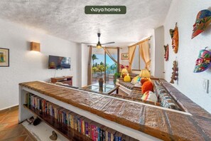 A living room with a sofa, a coffee table, a TV, and a bookshelf. - Puerto Vallarta 2BR/2BA Condo Near Beach, Pool & WiFi (Puerto Vallarta)
