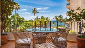 A balcony with a round table and wicker chairs, overlooking a pool and palm trees. - Puerto Vallarta 2BR/2BA Condo Near Beach, Pool & WiFi (Puerto Vallarta)