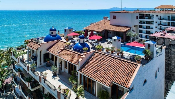 Un hôtel à plusieurs étages, doté d’une piscine et offrant une vue sur la mer.