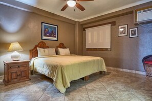 A bedroom with a bed, a nightstand, a ceiling fan, a projector screen, and framed pictures on the wall. - 204-Plaza Mar | 2BR Ocean View in Puerto Vallarta (Puerto Vallarta)