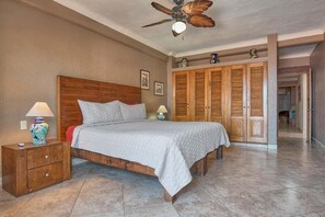Une chambre à coucher avec un lit en bois, des tables de chevet, un ventilateur de plafond et une armoire.