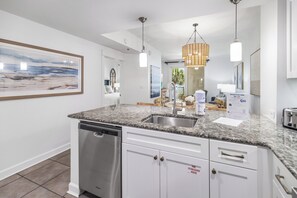 A modern kitchen with granite countertops, stainless steel appliances, and a built-in dishwasher.