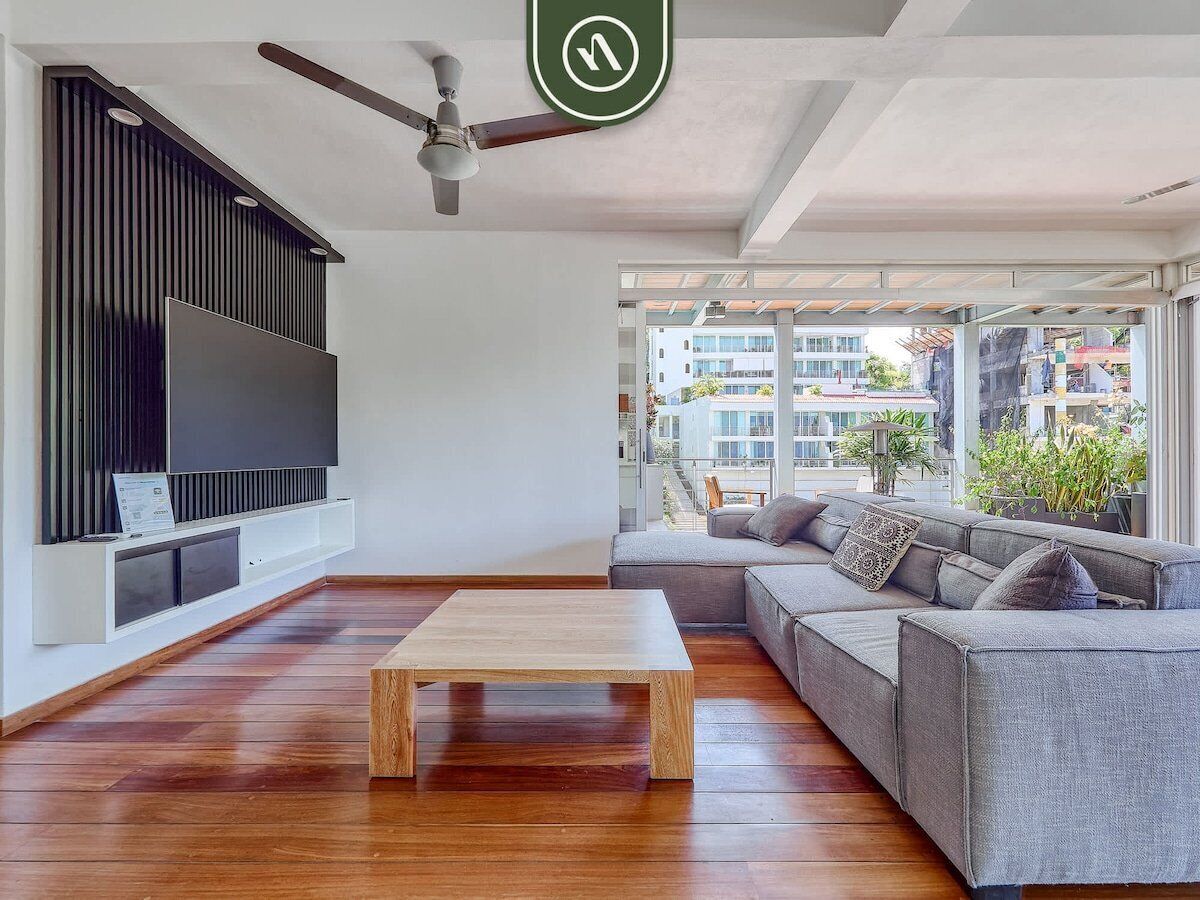 A modern living room with a flat-screen TV, a wooden coffee table, and a grey sofa.
