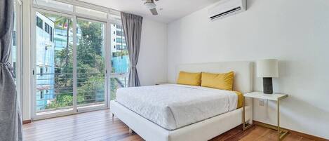 Ein Schlafzimmer mit großem Fenster, einem Bett, einem Deckenventilator und einer Klimaanlage.