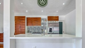 A modern kitchen with wooden cabinets, a stainless steel refrigerator, and a patterned backsplash. - The Ava Unit 16 | 2BR/3BA Puerto Vallarta, pool, gym, hot tub (Puerto Vallarta)