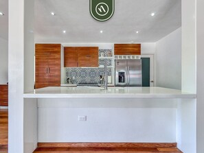 A modern kitchen with wooden cabinets, a stainless steel refrigerator, and a patterned backsplash. - The Ava Unit 16 | 2BR/3BA Puerto Vallarta, pool, gym, hot tub (Puerto Vallarta)