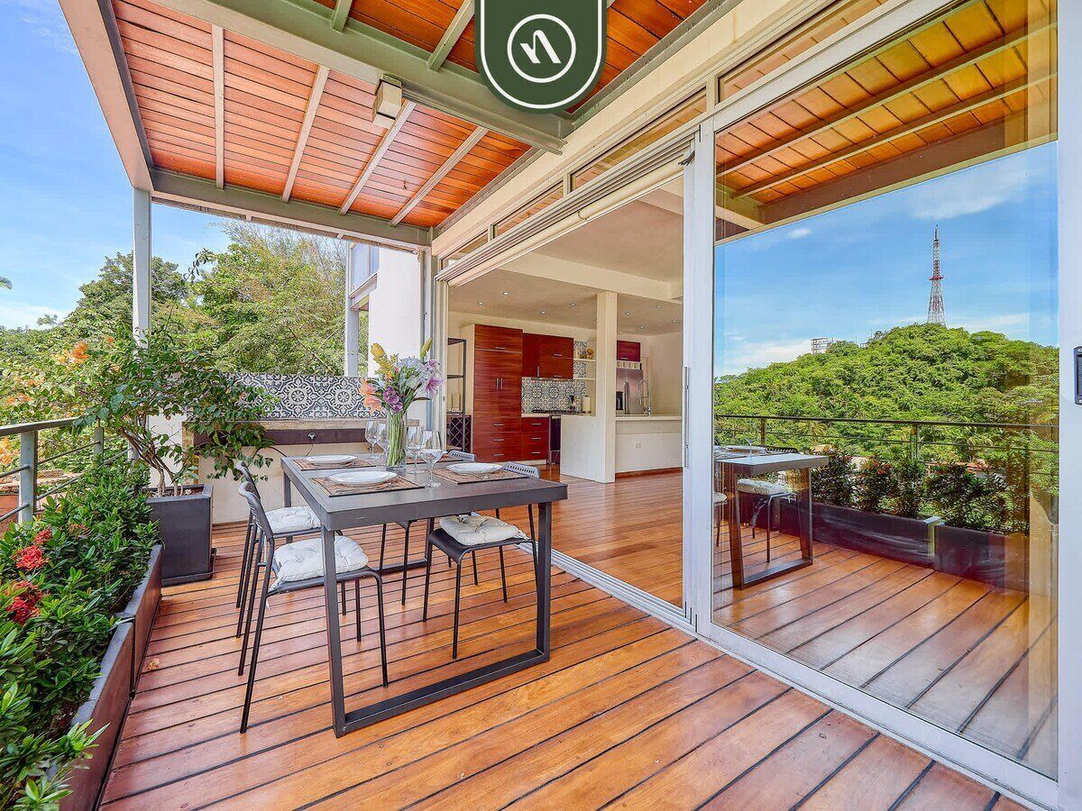 A spacious outdoor deck with a dining area, a kitchen, and a view of a tower.