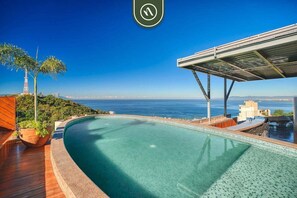 A swimming pool with a view of the ocean and a palm tree. - The Ava Unit 16 | 2BR/3BA Puerto Vallarta, pool, gym, hot tub (Puerto Vallarta)
