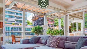 Uma área de estar moderna ao ar livre, com um sofá modular cinza, uma cadeira de madeira e uma mesa.