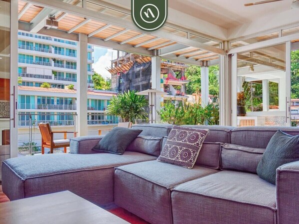 A modern outdoor seating area with a grey sectional sofa, a wooden chair, and a table.