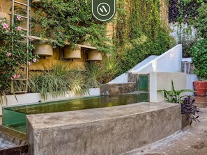A courtyard with a water feature, potted plants, and a building with balconies. - The Ava Unit 16 | 2BR/3BA Puerto Vallarta, pool, gym, hot tub (Puerto Vallarta)