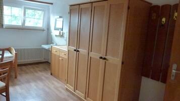 Ein Zimmer mit Holzschrank, Heizkörper, Spüle und Fenster.