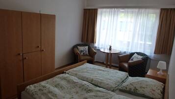 Ein Hotelzimmer mit einem Bett, zwei Stühlen, einem kleinen Tisch und einem Kleiderschrank.