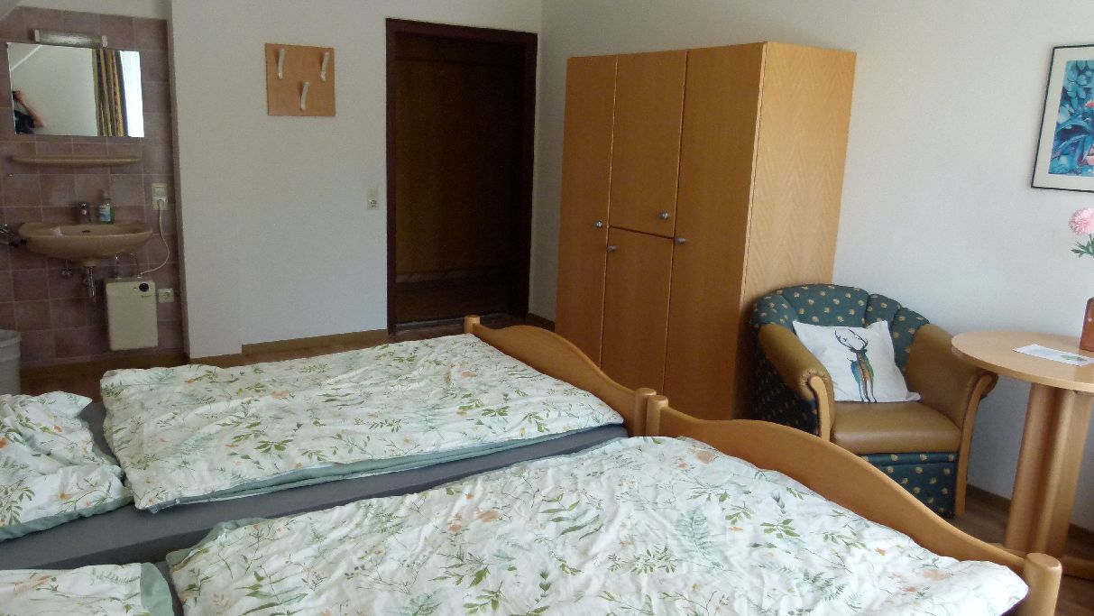 Een slaapkamer met een bed, een stoel, een garderobe en een kleine tafel.