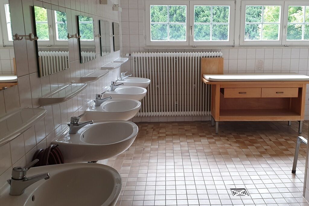 Ein Badezimmer mit vier Waschbecken, einem Holzkonsolenunterschrank und einer Heizung.