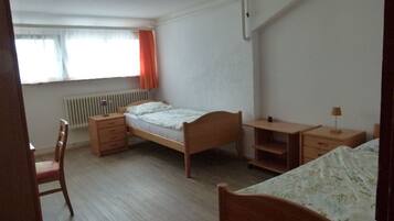 Ein Schlafzimmer mit einem Einzelbett, einem Schreibtisch, einem Stuhl und einer Heizung.