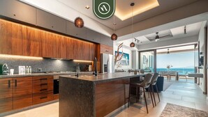 A modern kitchen with a central island, wooden cabinets, and pendant lighting. - "Private Ocean Sanctuary | Quiet Luxury." (Puerto Vallarta)