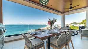 A dining area with a view of the ocean, a ceiling fan, and wicker chairs. - "Private Ocean Sanctuary | Quiet Luxury." (Puerto Vallarta)