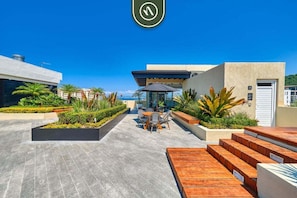 A rooftop patio with outdoor seating, a pool, and a view of the ocean.